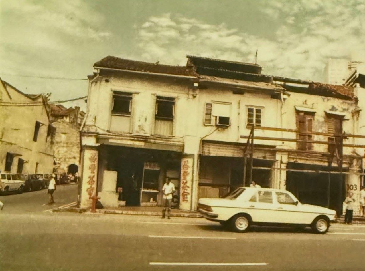 Old photograph of the coffeeshop in a row of shophouses, with a car in front